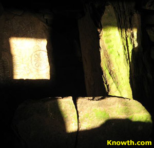 Loughcrew equinox sunlight on a chamber orthostat carved with a rayed sun circle, zigzags and chevrons.