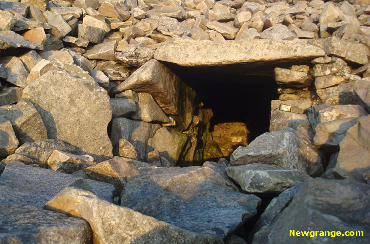 Beam of golden light from the setting sun entering the passage of the cairn on Slieve Gullion