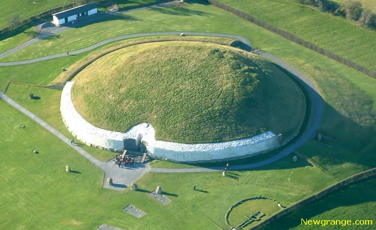 Aerial view of Newgrange mound with white quartz facade, kerbstones, standing stones and visitors.